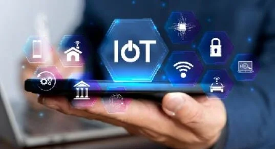 A hand holding a tablet with glowing IoT icons and hexagonal network symbols, illustrating the Internet of Things.