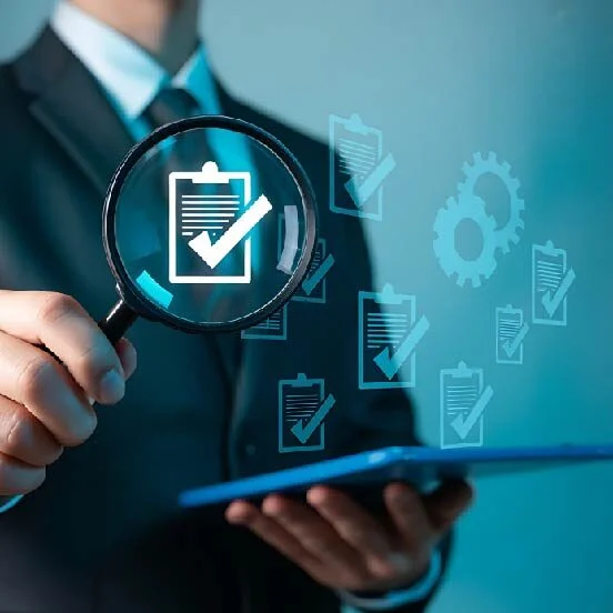 Businessperson in a suit examines a checklist with a magnifying glass, symbolizing auditing and quality control.