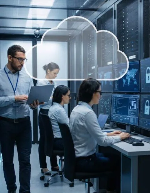 IT professionals in a data center monitor dashboards on multiple screens; a cloud icon overlay suggests cloud computing and data security.